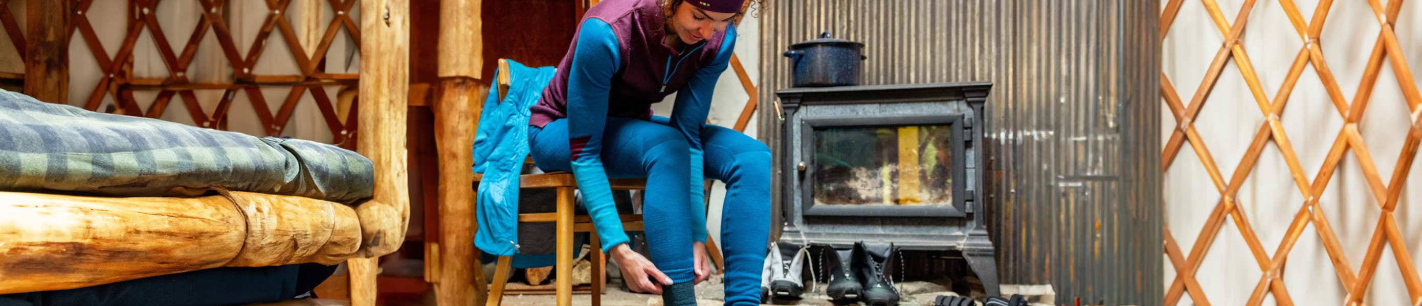 Woman by fire putting on smartwool base layer pants
